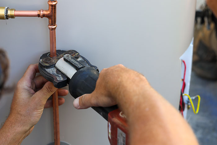 Plumber compressing copper piping on a hot water system in Maroochydore